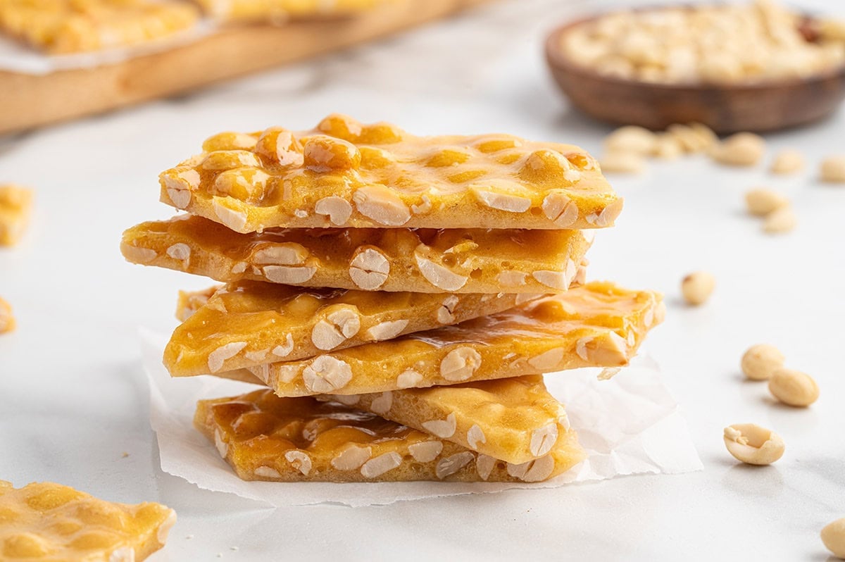 Stacked pieces of peanut brittle on parchment paper.