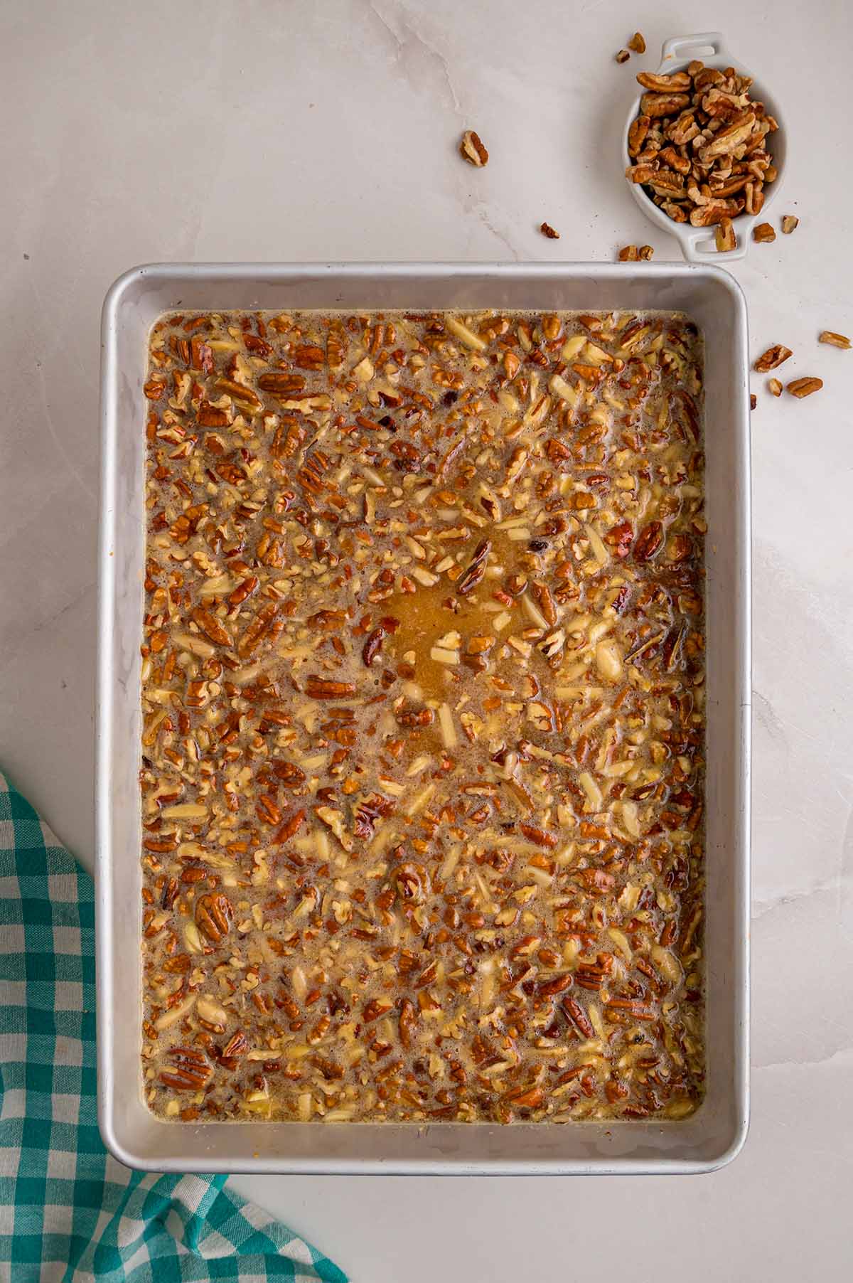Pecan filling spread over the crust in a baking pan, ready to bake.