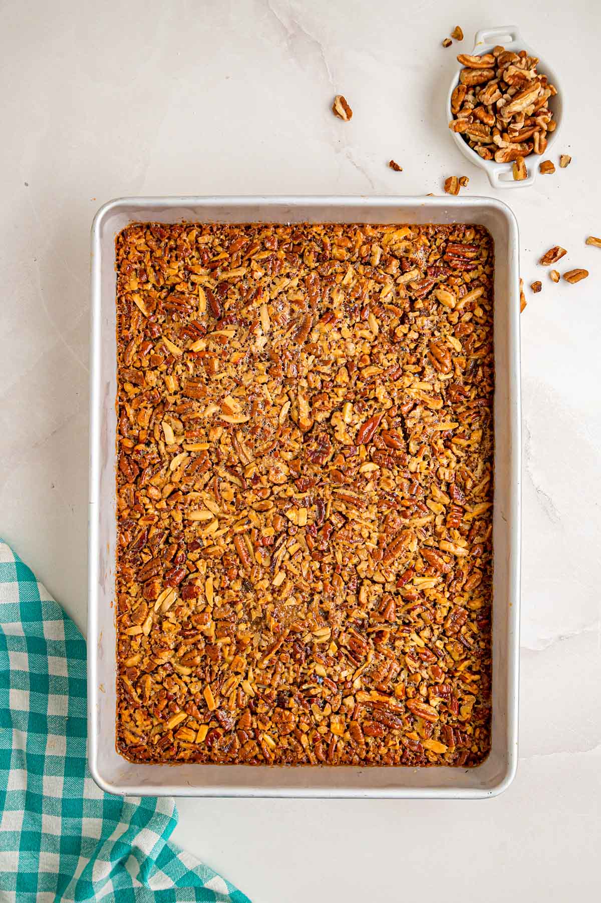 Baked pecan pie bars with a golden, caramelized pecan topping in a baking pan.
