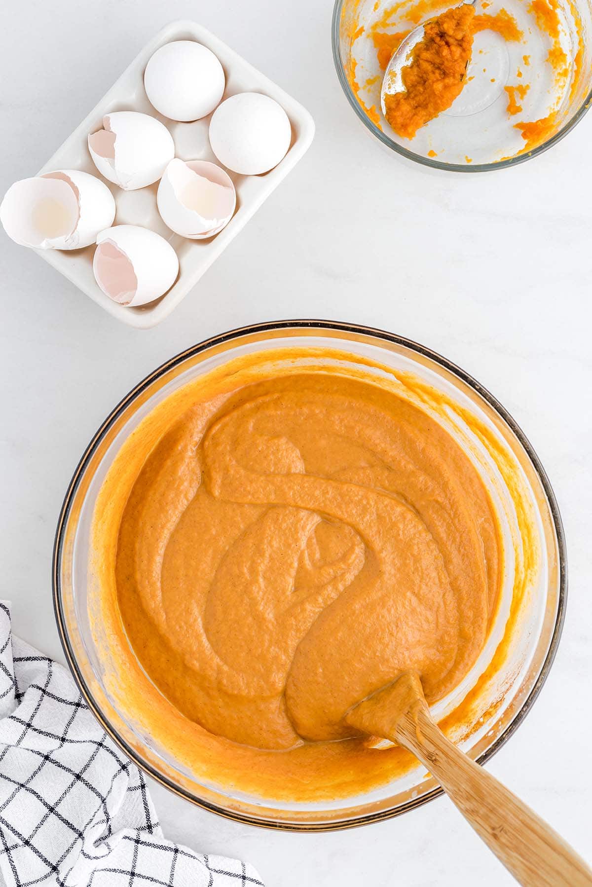 Pumpkin dump cake batter mixed in a bowl with eggs and pumpkin puree.
