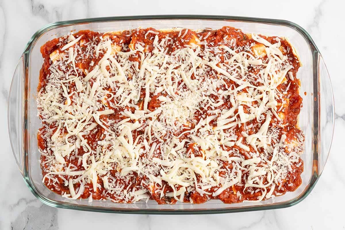 Shredded cheese sprinkled over ravioli lasagna before baking.