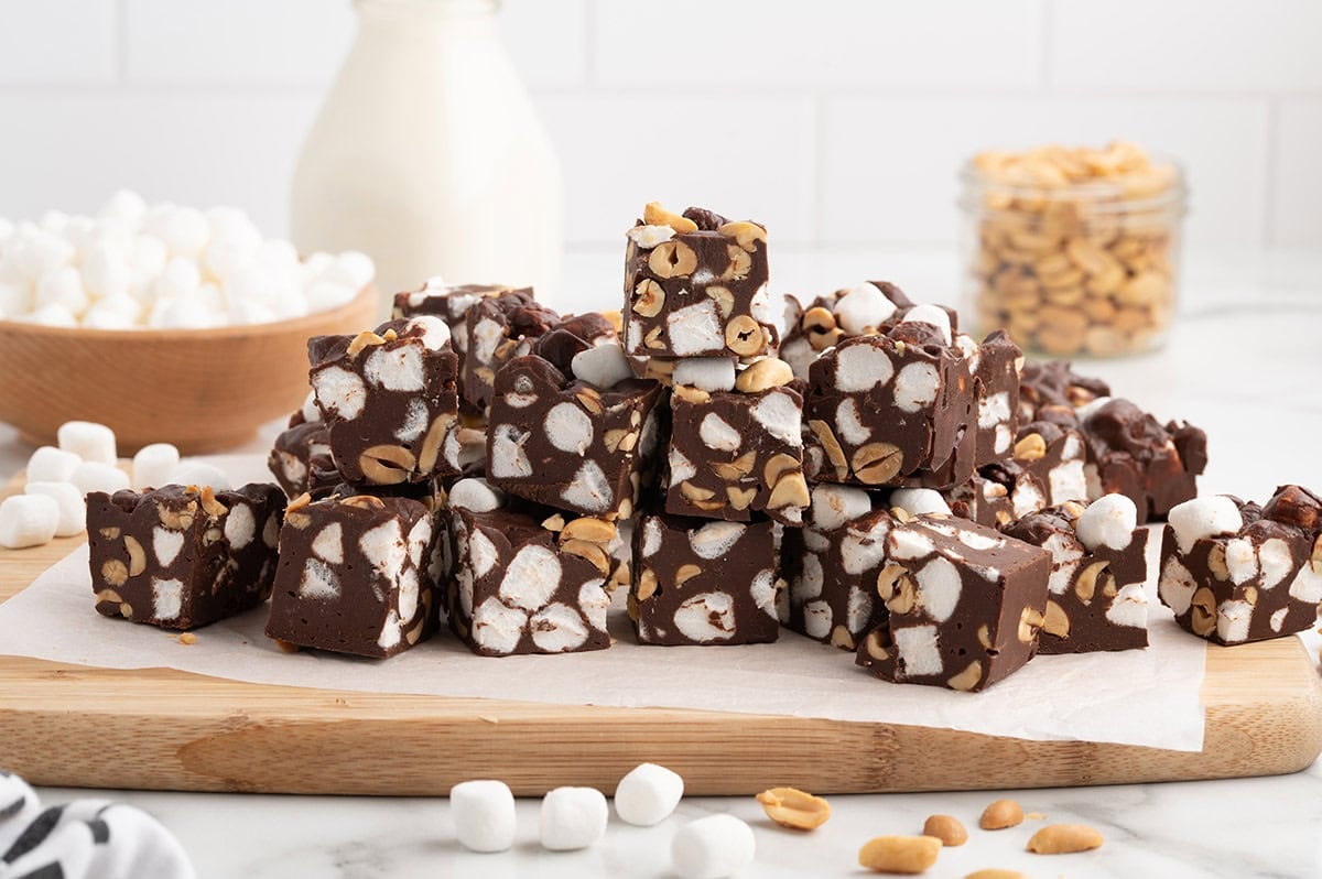 Homemade Rocky Road Fudge squares loaded with fluffy mini marshmallows and crunchy peanuts, piled on a serving board.