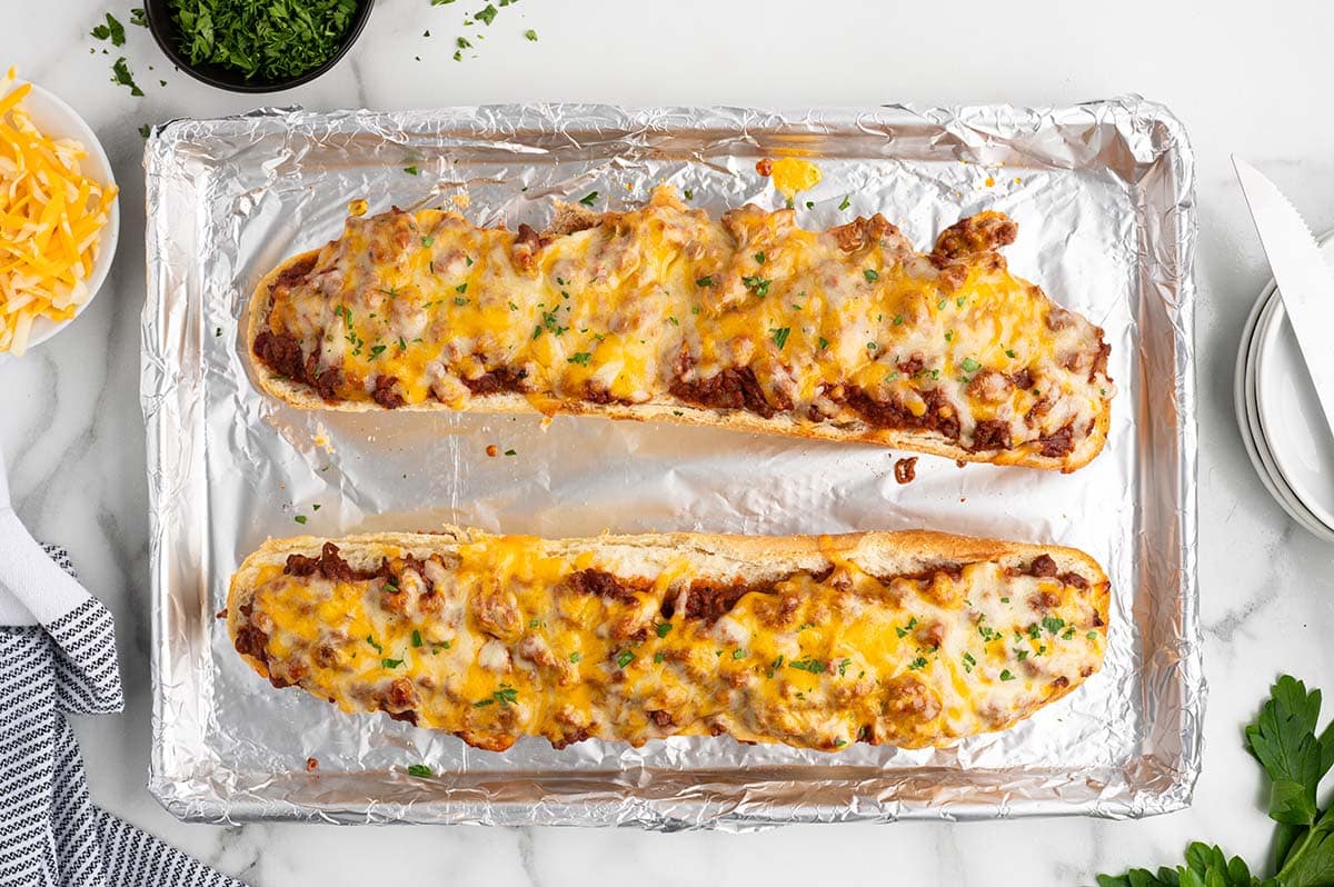 Baked sloppy joe garlic bread topped with melted cheese on a foil-lined baking sheet.