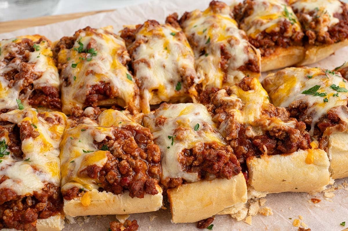 Rows of sliced sloppy joe breadsticks topped with cheesy meat sauce.