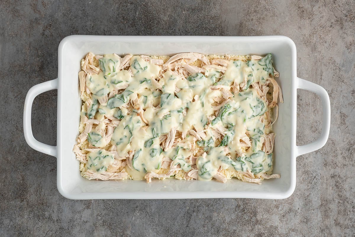 Top the ricotta layer with shredded chicken, then spoon the creamy spinach sauce evenly over the chicken so every bite stays rich and flavorful.