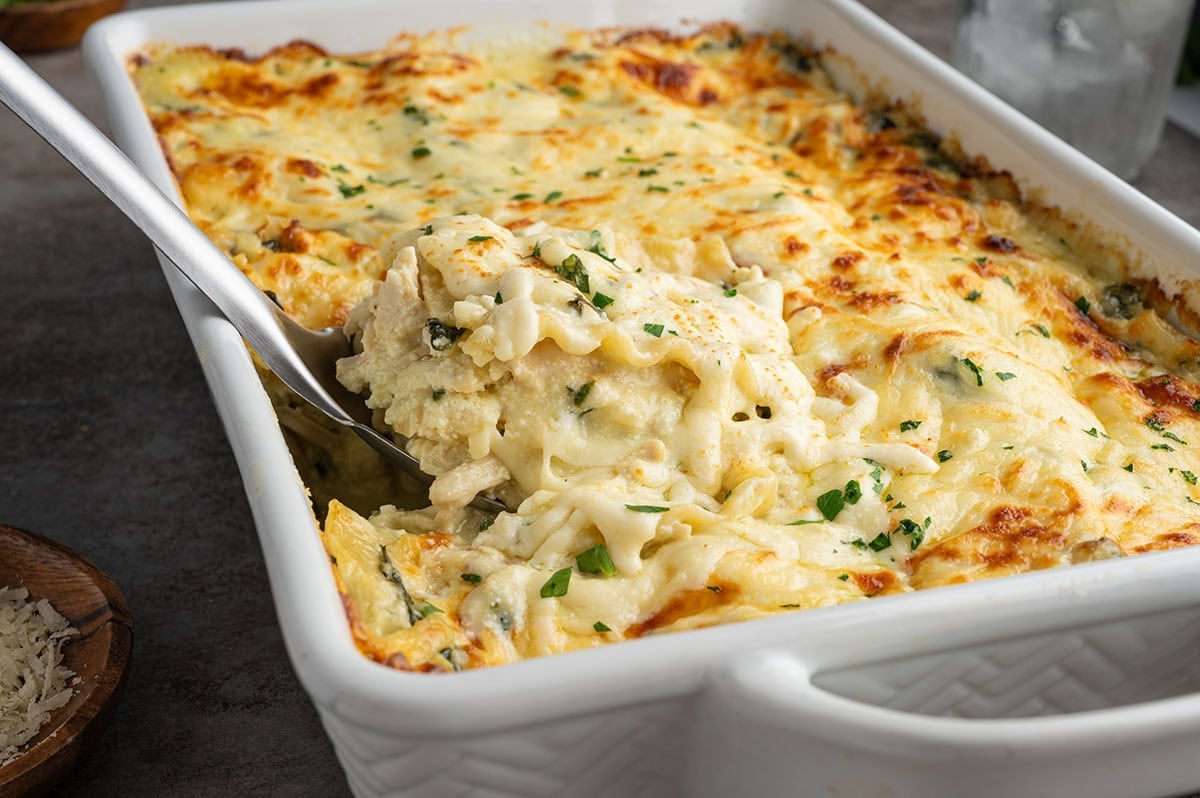 a slice of white chicken lasagna lifted up from the casserole dish.