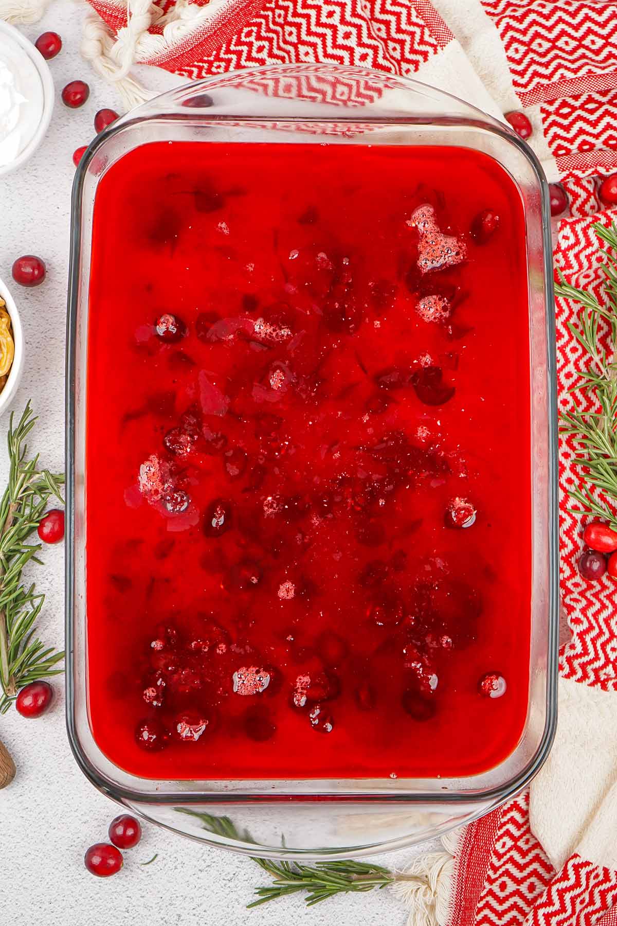 Red cranberry gelatin layer poured over the creamy filling in a glass baking dish.
