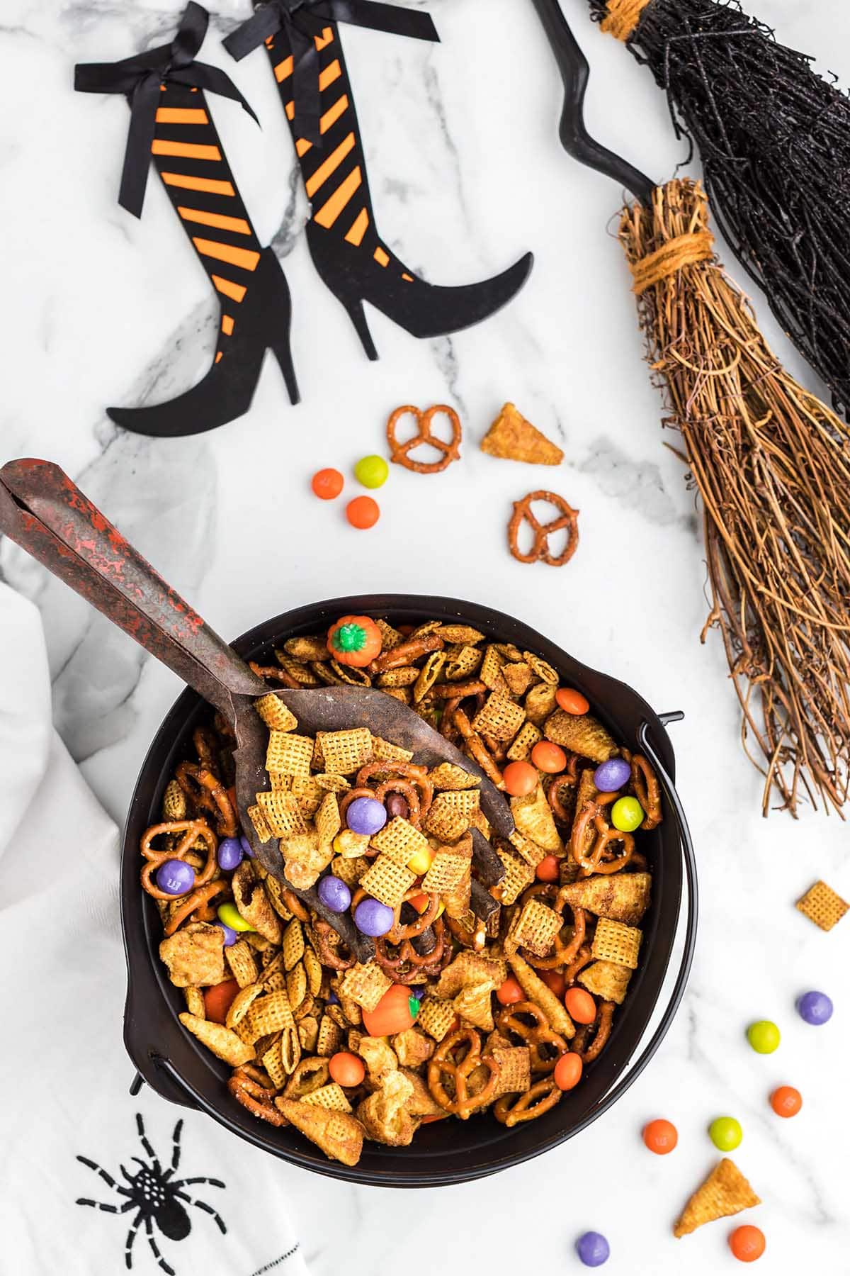 Halloween Chex mix in a cauldron with witch decor.