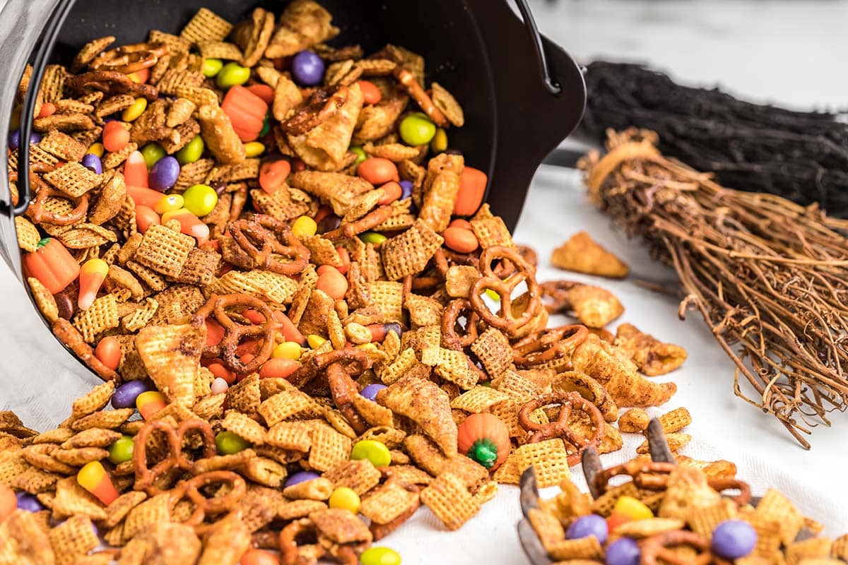 Close-up of Halloween Chex mix spilling from a cauldron.