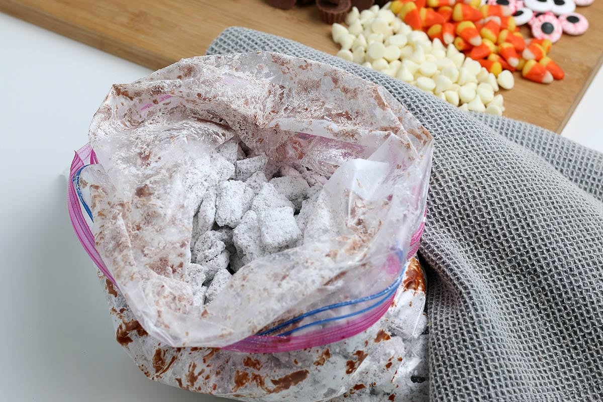 Chocolate-coated cereal being tossed with powdered sugar in a zip-top bag.