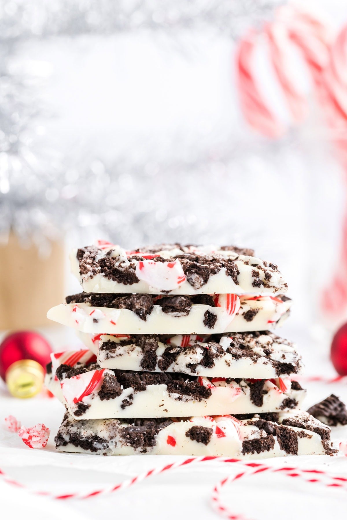 Stacked pieces of Oreo peppermint bark with Christmas ornaments in the background.