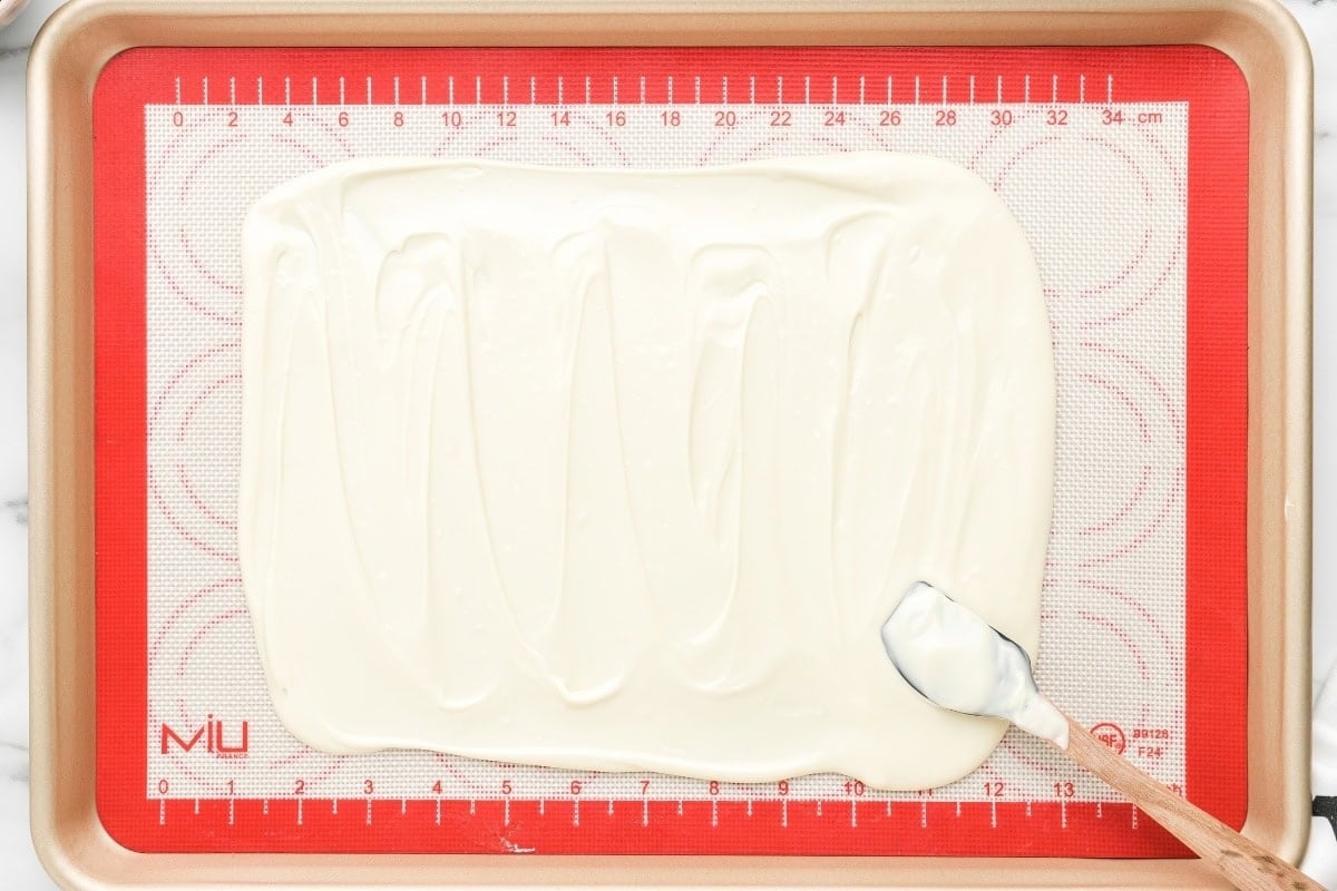 Melted white chocolate spread on a baking sheet.