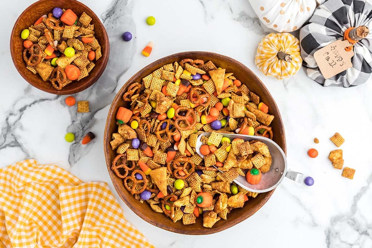 Overhead view of pumpkin spice snack mix in a wooden bowl with fall decor.