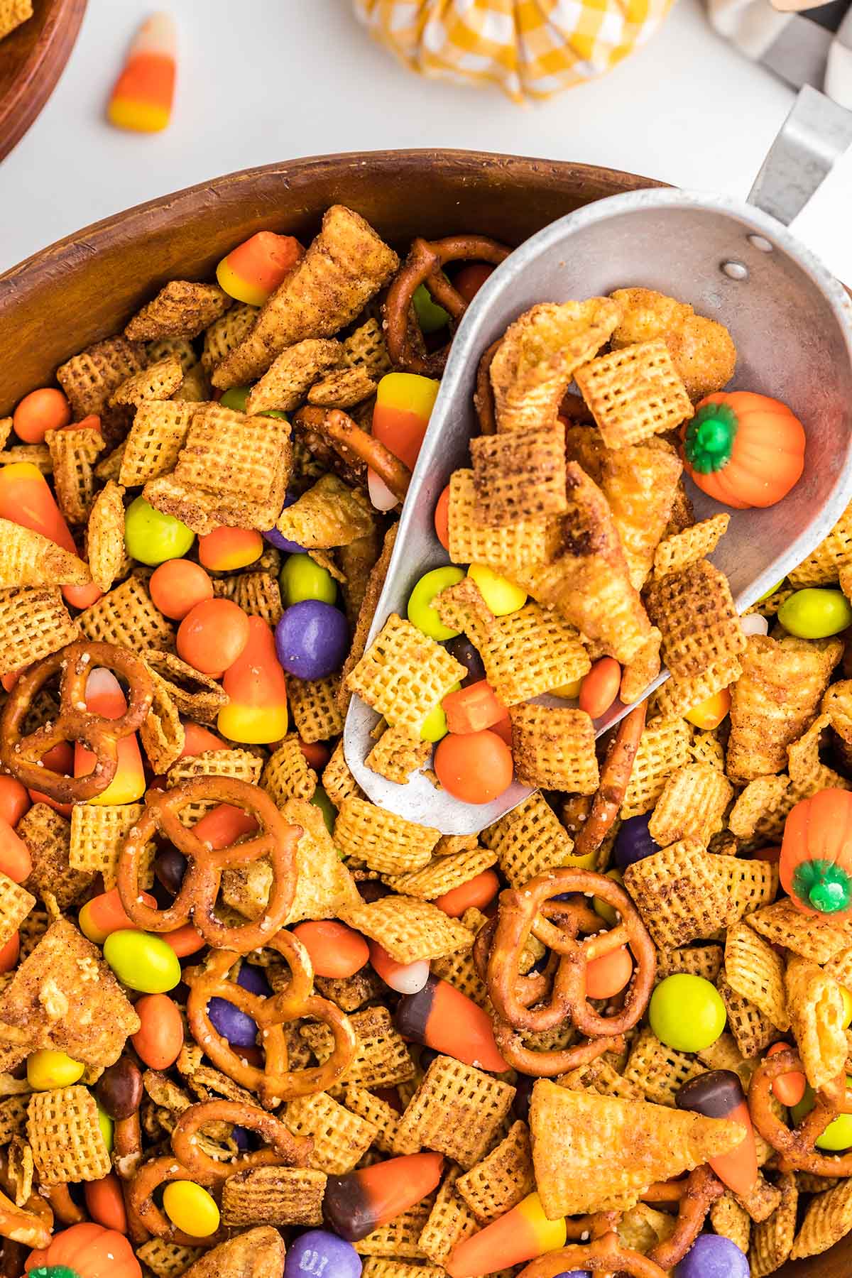 Close-up of pumpkin spice snack mix with a scoop and candy pumpkin.