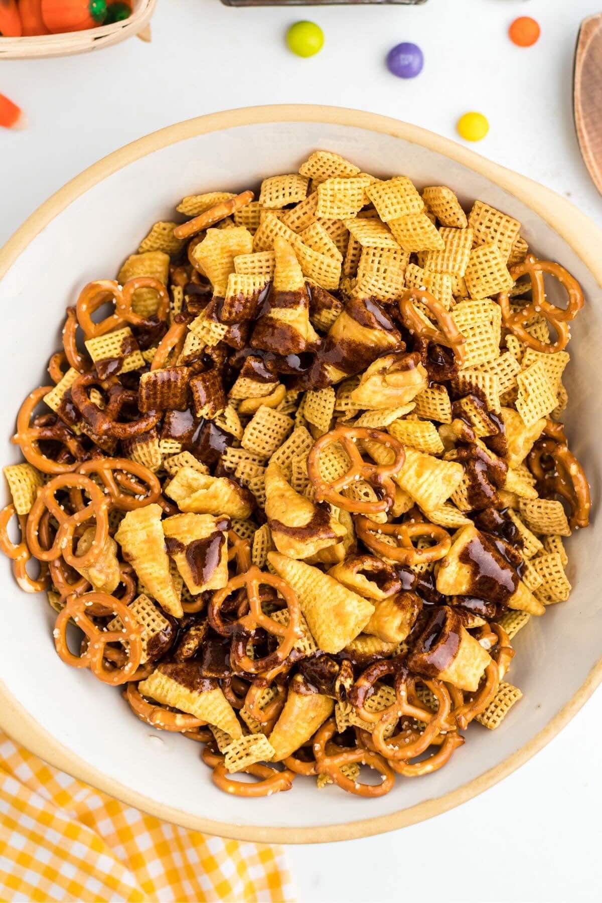 Chex mix and pretzels drizzled with pumpkin spice glaze in a bowl.