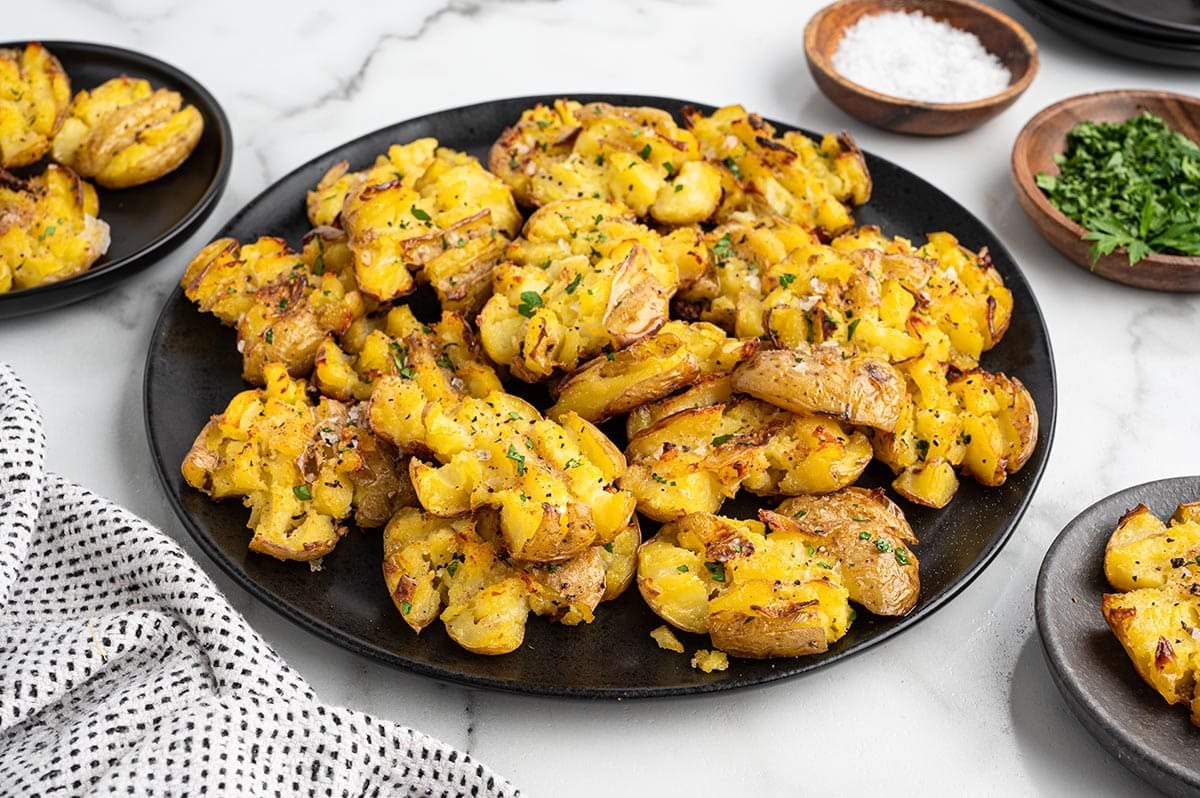 Plate of crispy smashed potatoes garnished with parsley.