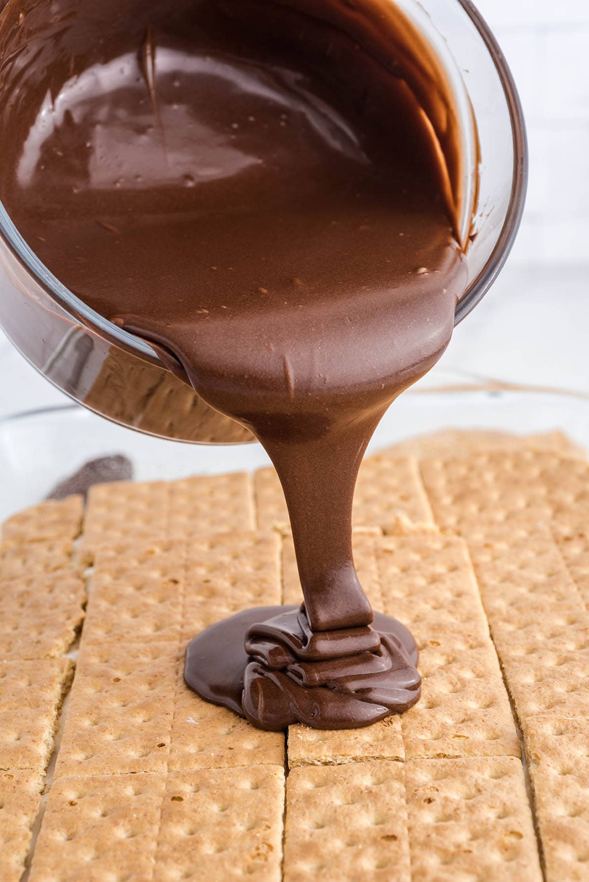 pouring the chocolate on top of graham crackers layer.