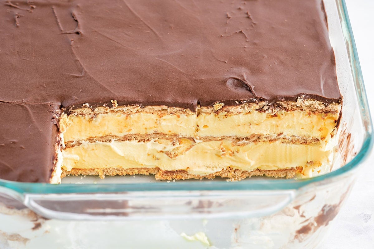 Close-up of eclair cake in a glass dish, showing the chocolate topping and creamy layered filling.
