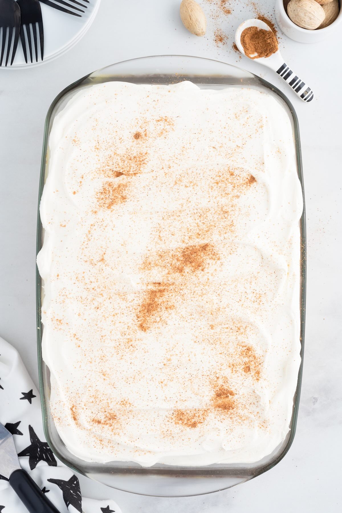 Eggnog poke cake topped with whipped cream and a dusting of cinnamon, ready to serve.