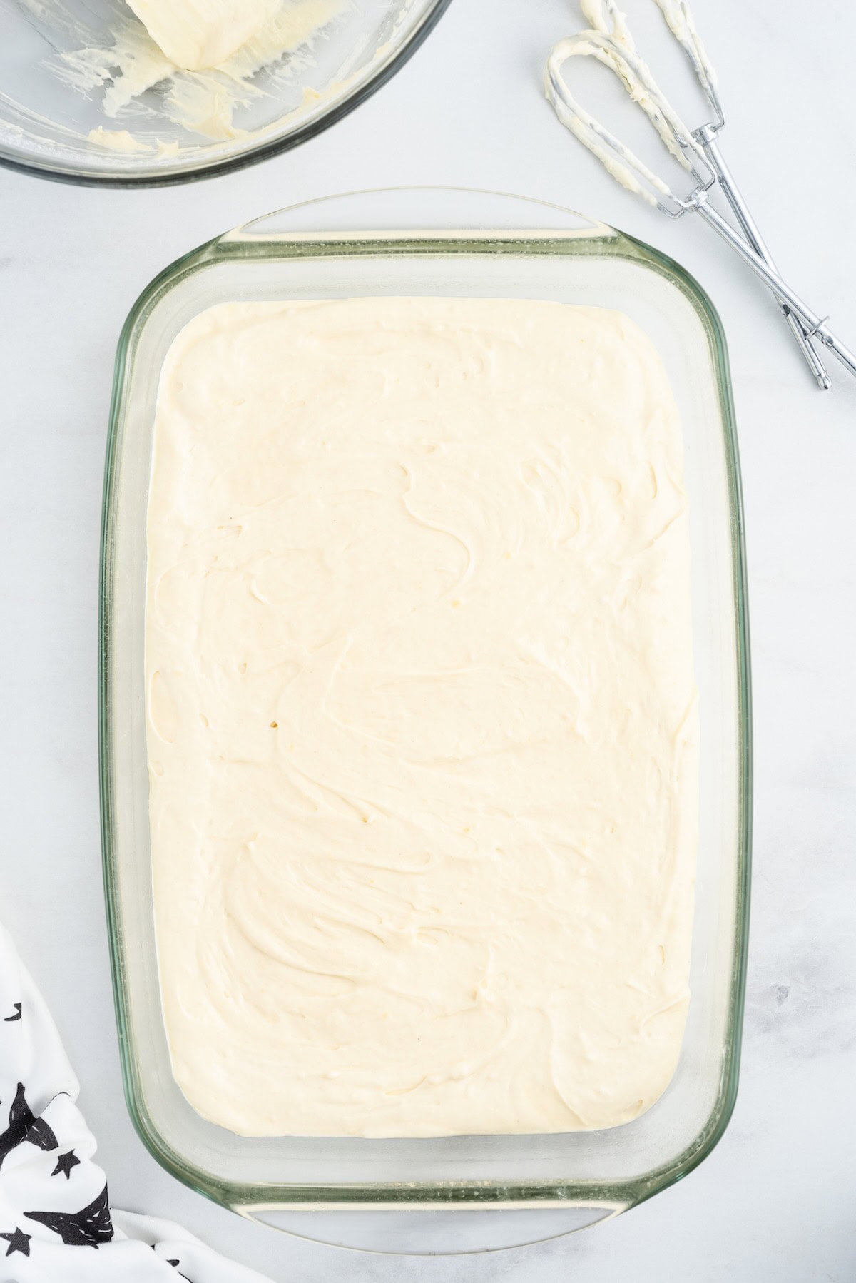 Cake batter spread evenly in a glass baking dish before baking.