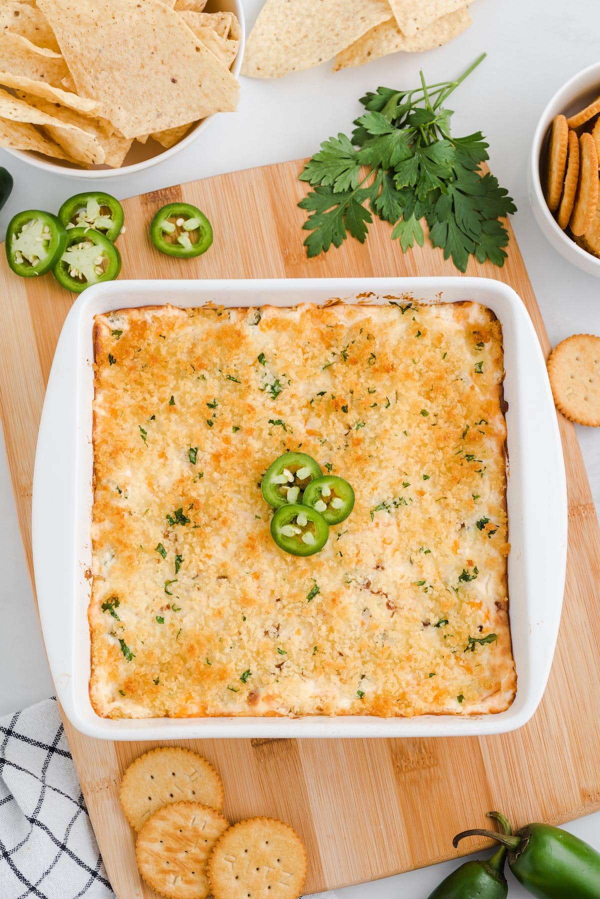 Baked jalapeño popper dip topped with jalapeño slices, served with chips and crackers.