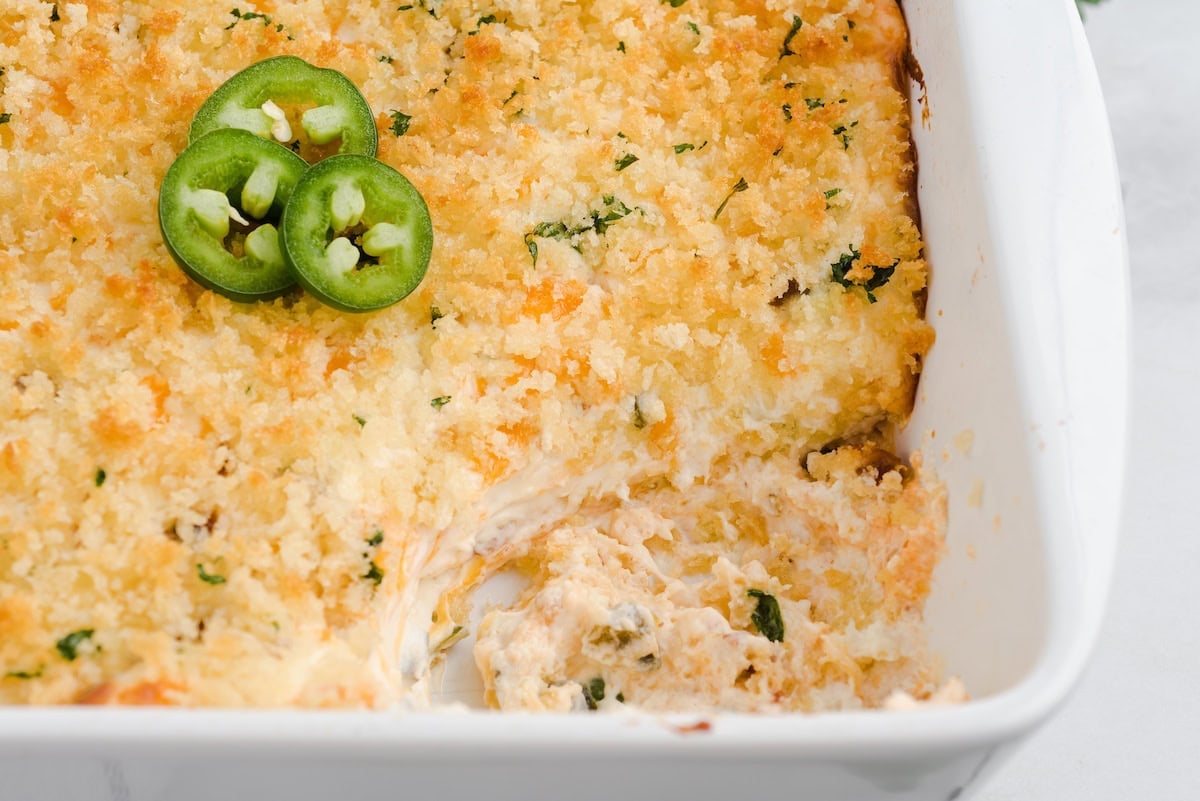 Close-up of baked jalapeño popper dip with a scoop removed.