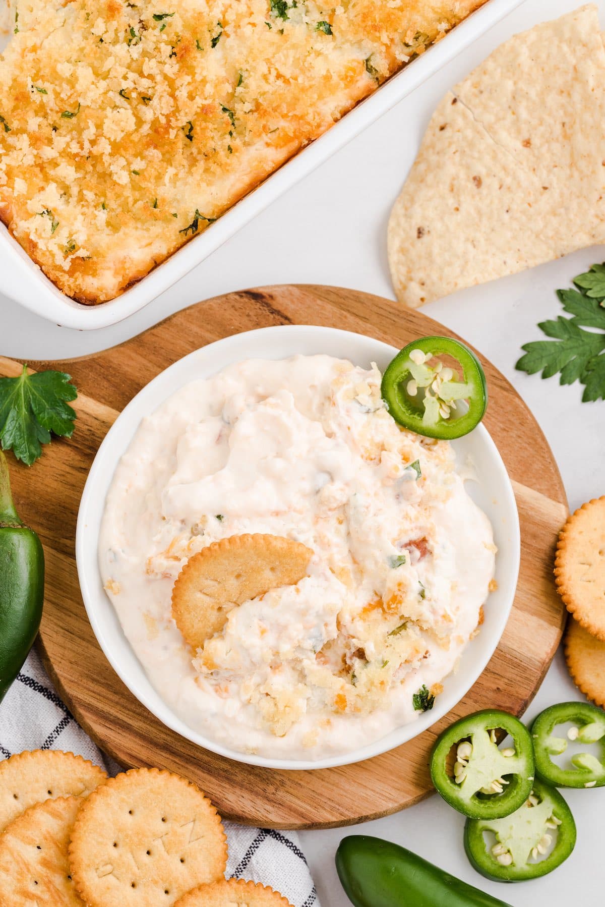 Bowl of jalapeño popper dip with a cracker, served with chips and crackers.