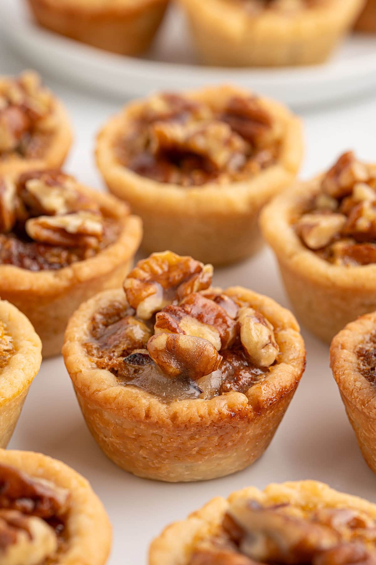 Close-up of mini pecan pies with buttery crusts and caramelized pecan topping.