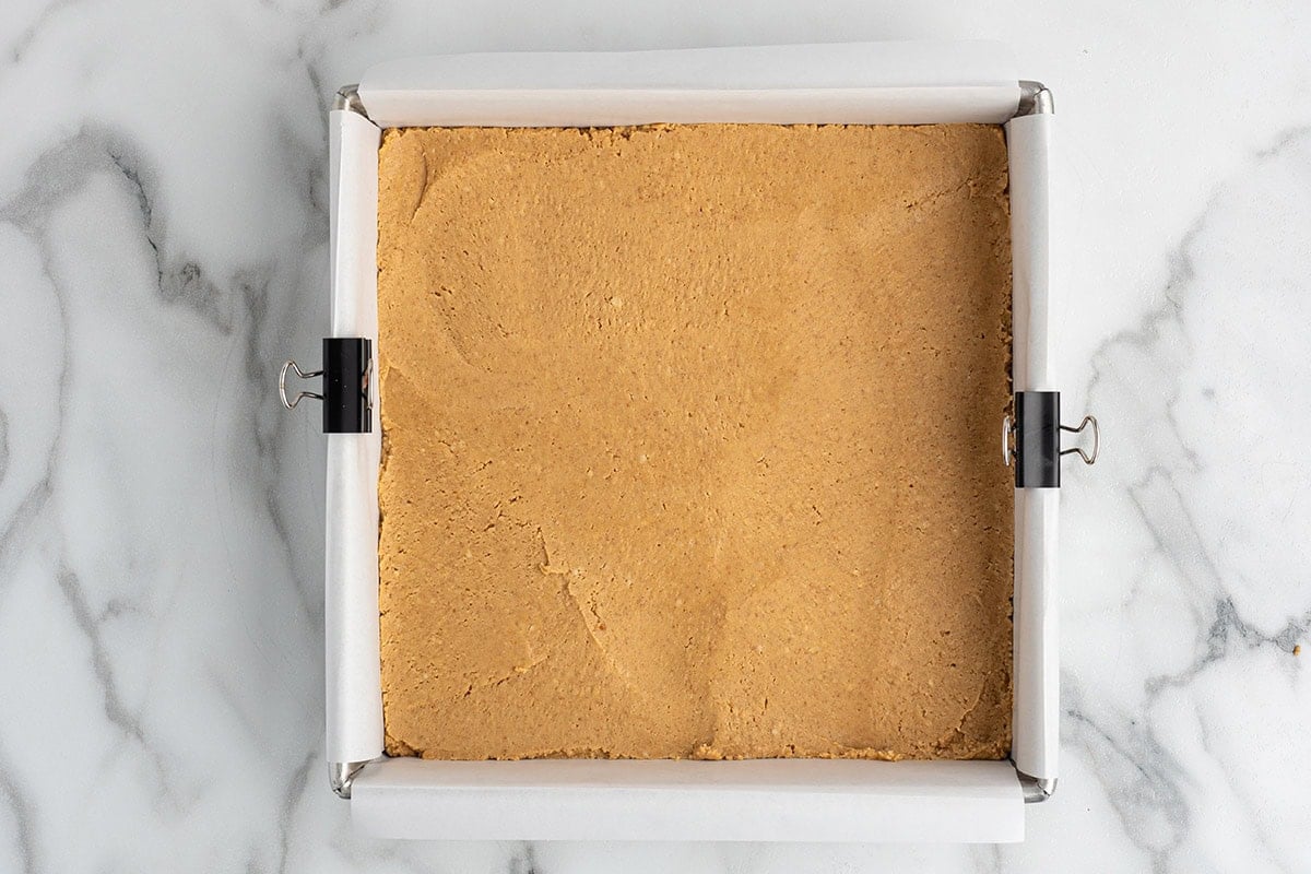 press the peanut butter base in square baking pan lined with parchment paper. 