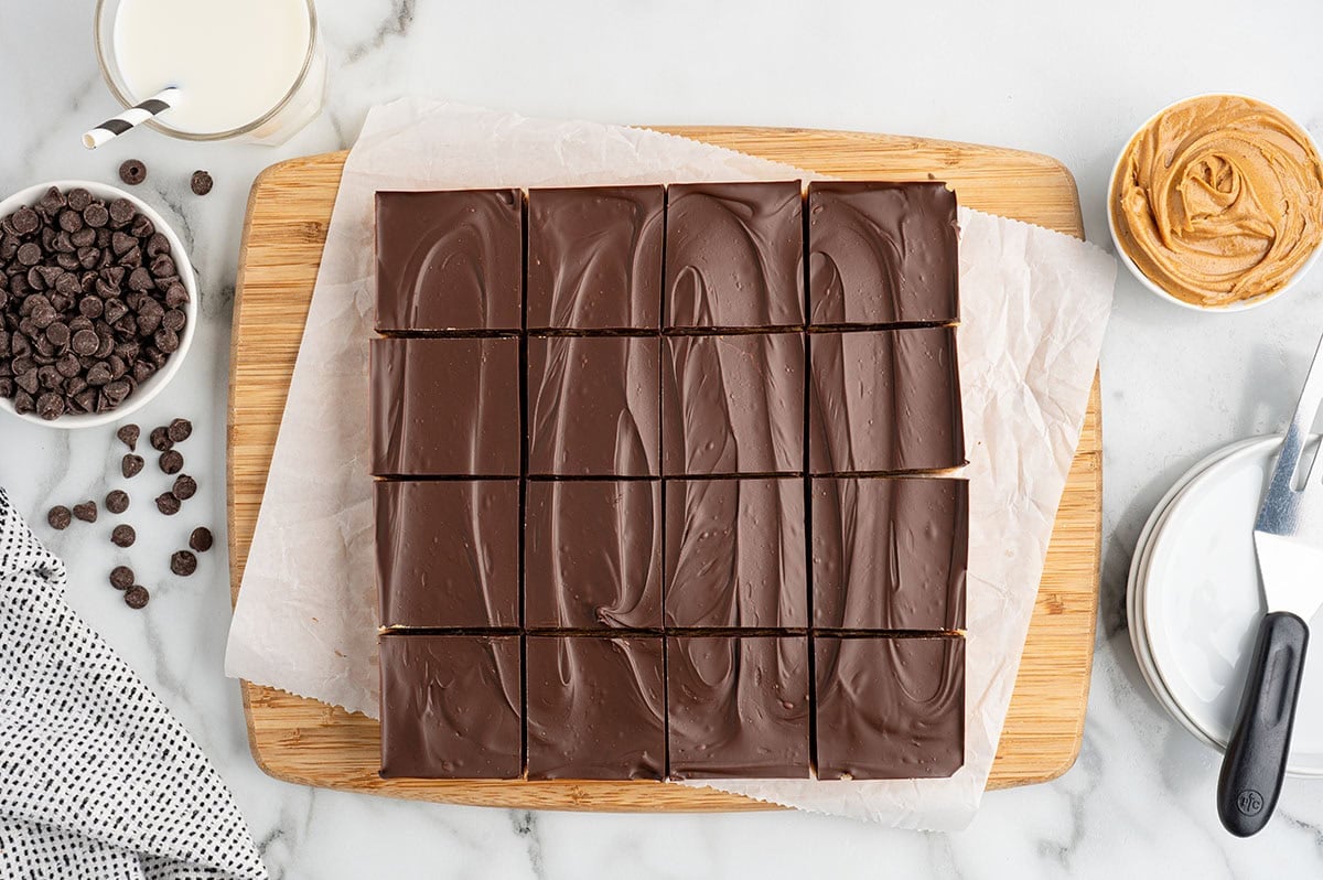 no bake peanut butter bars cut into 16 squares and placed on top of wooden board. 
