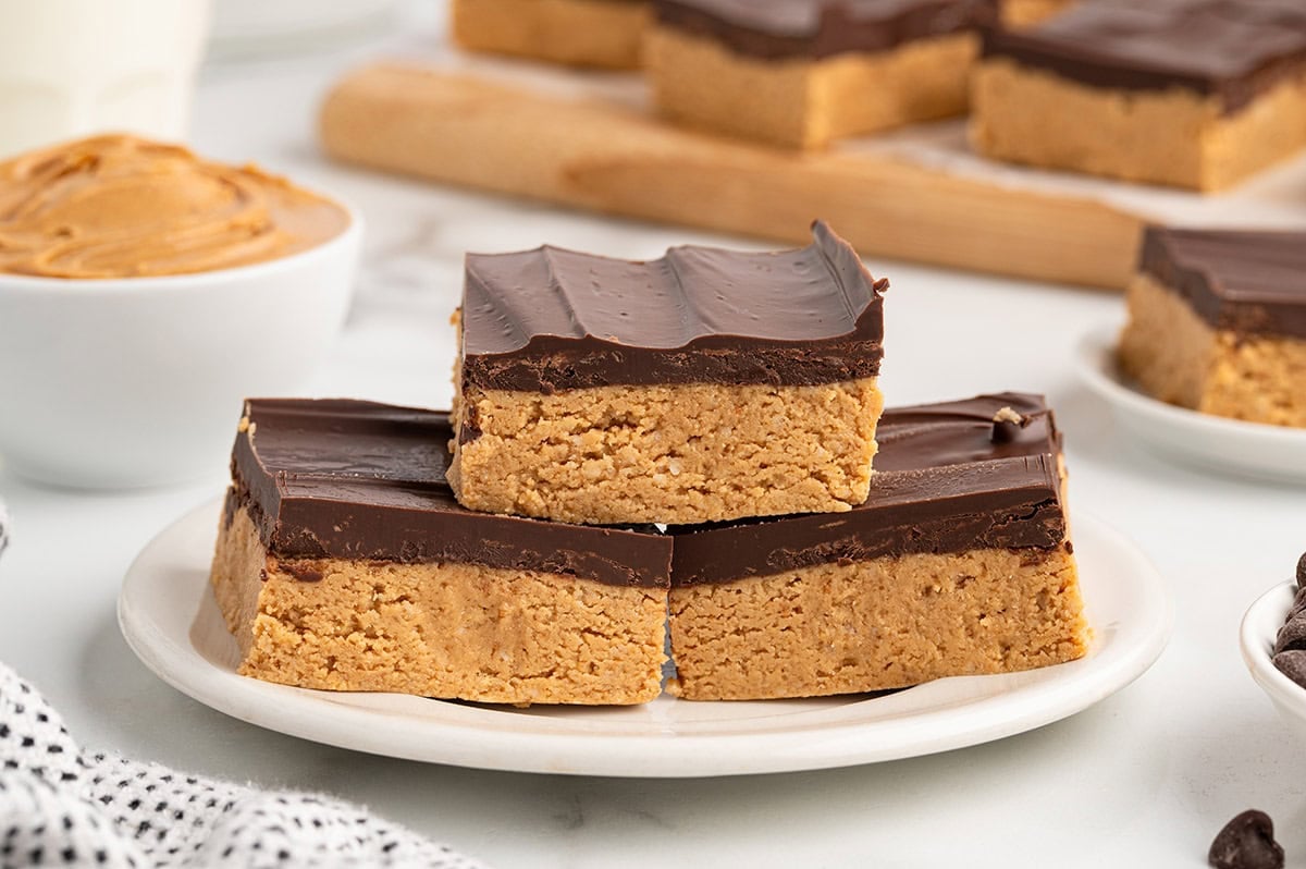 peanut butter bars stacked on top of white plate. 