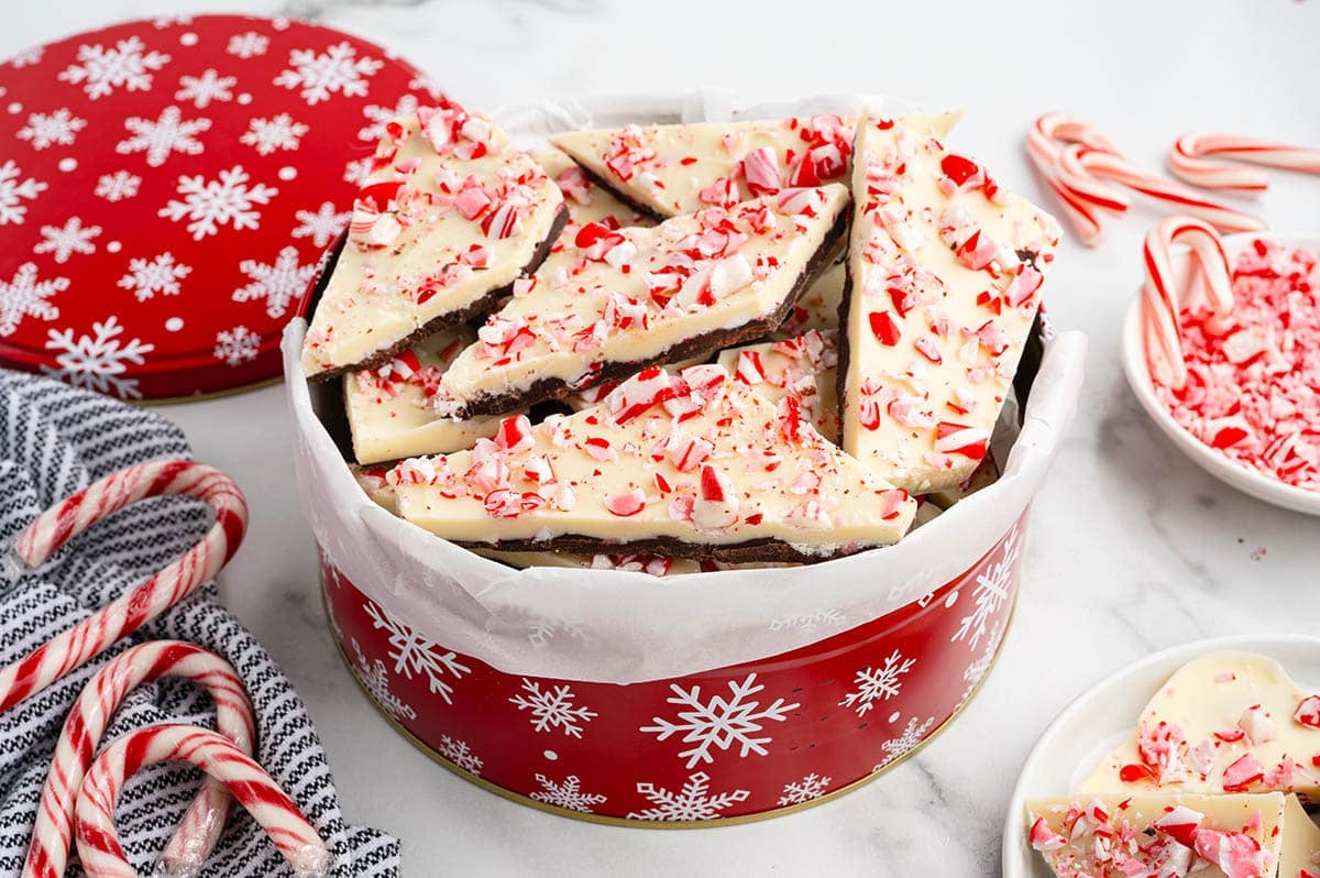 Peppermint bark pieces topped with crushed candy cane in a snowflake tin.