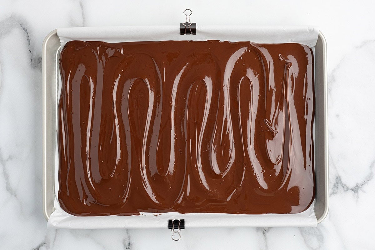 Peppermint bark chocolate layer spread on a baking sheet.