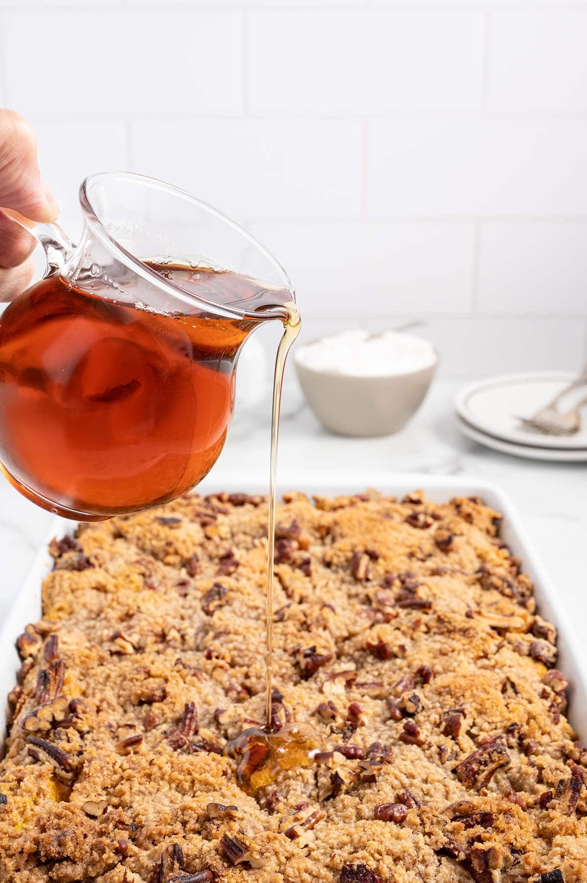 Syrup being poured over pumpkin French toast casserole with pecans.
