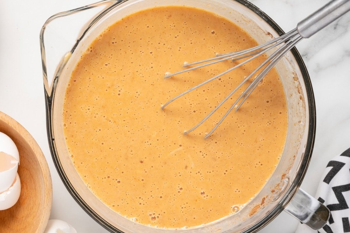 Bread cubes coated in pumpkin custard in a baking dish.