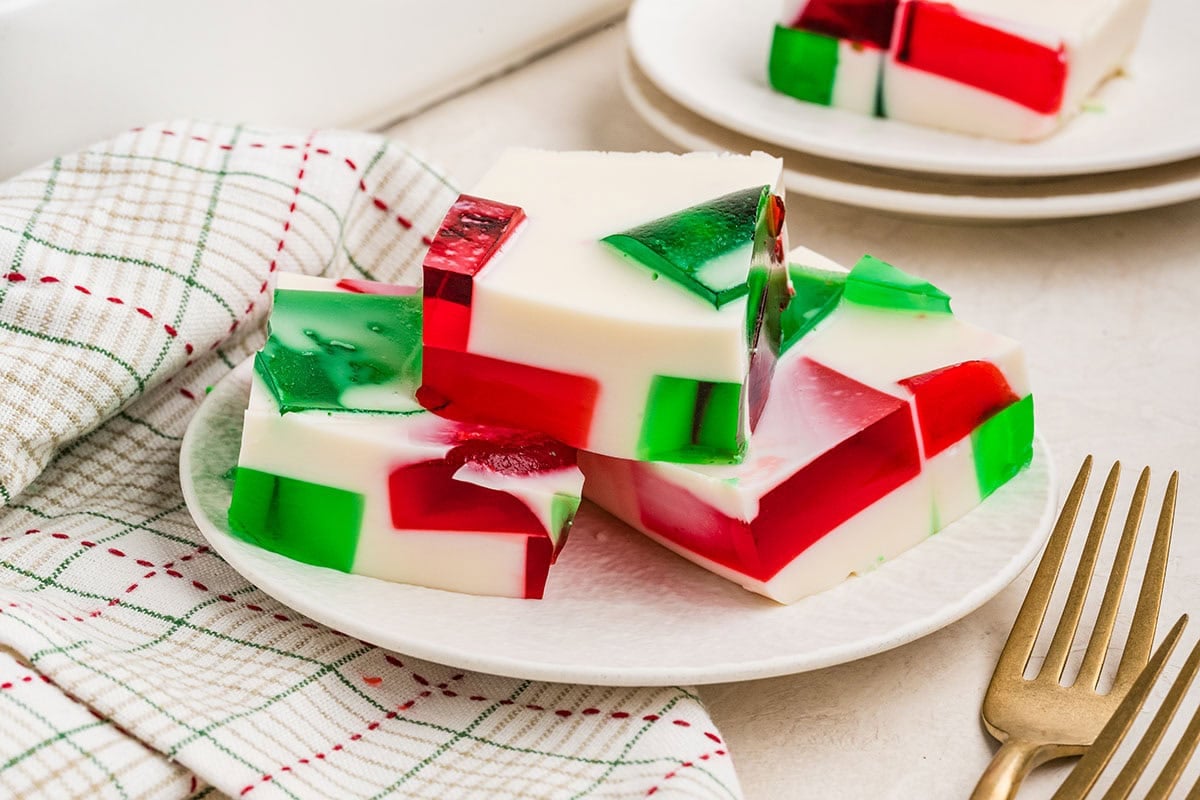Red, green, and white Christmas Jello squares on a plate.