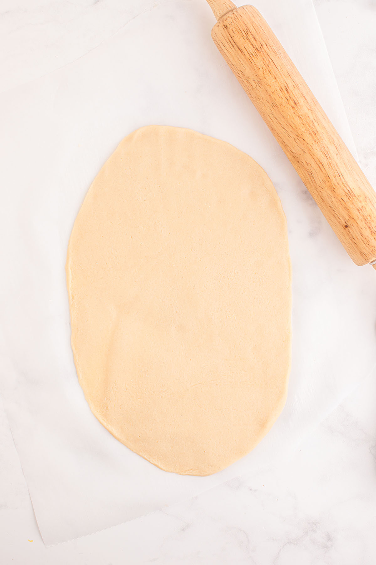 Rolled sugar cookie dough with a rolling pin.