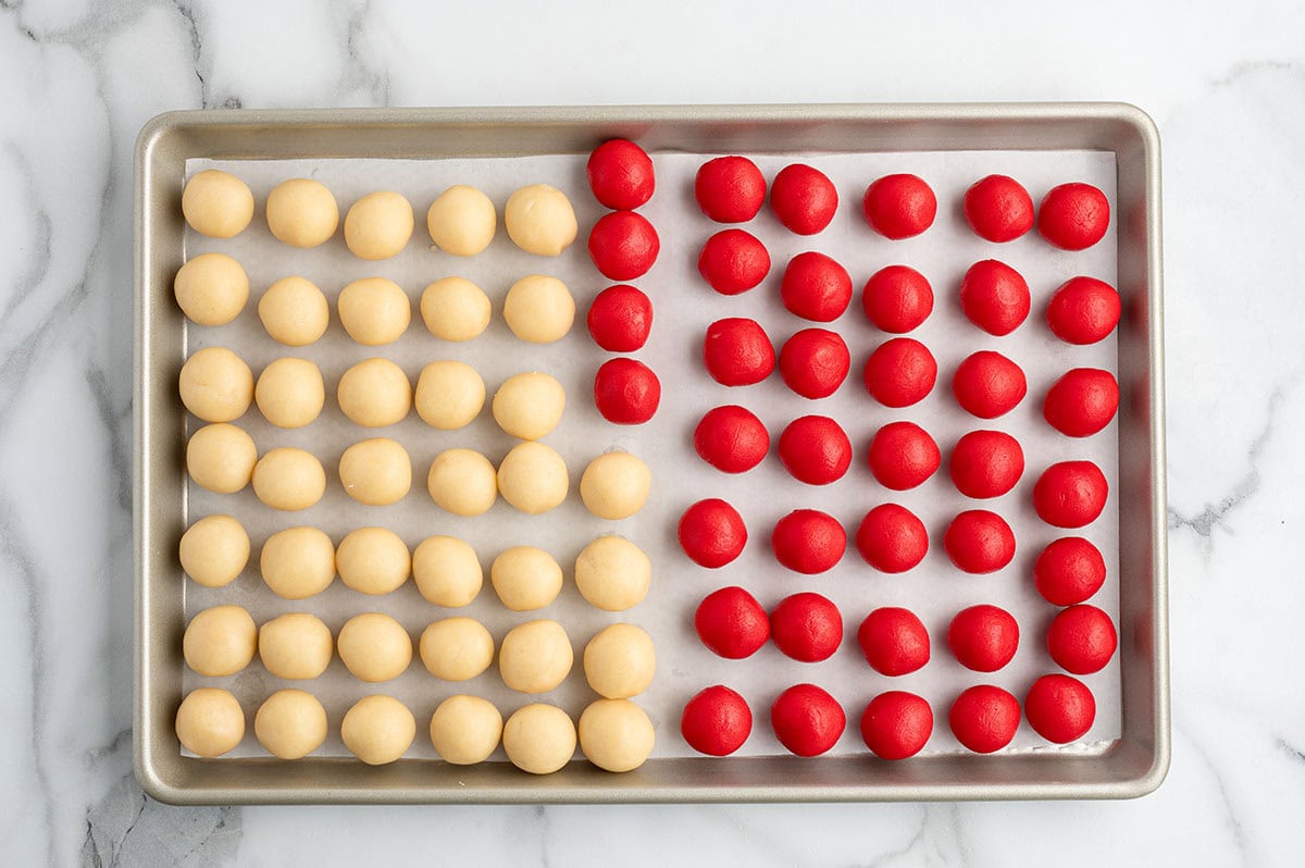 Red and plain dough rolled into strands and twisted together to form a candy cane shape.