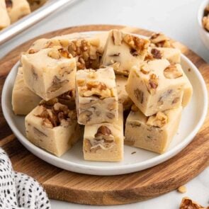 Maple walnut fudge squares stacked on a white plate.
