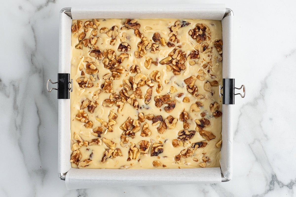 Maple walnut fudge topped with chopped walnuts in a pan.