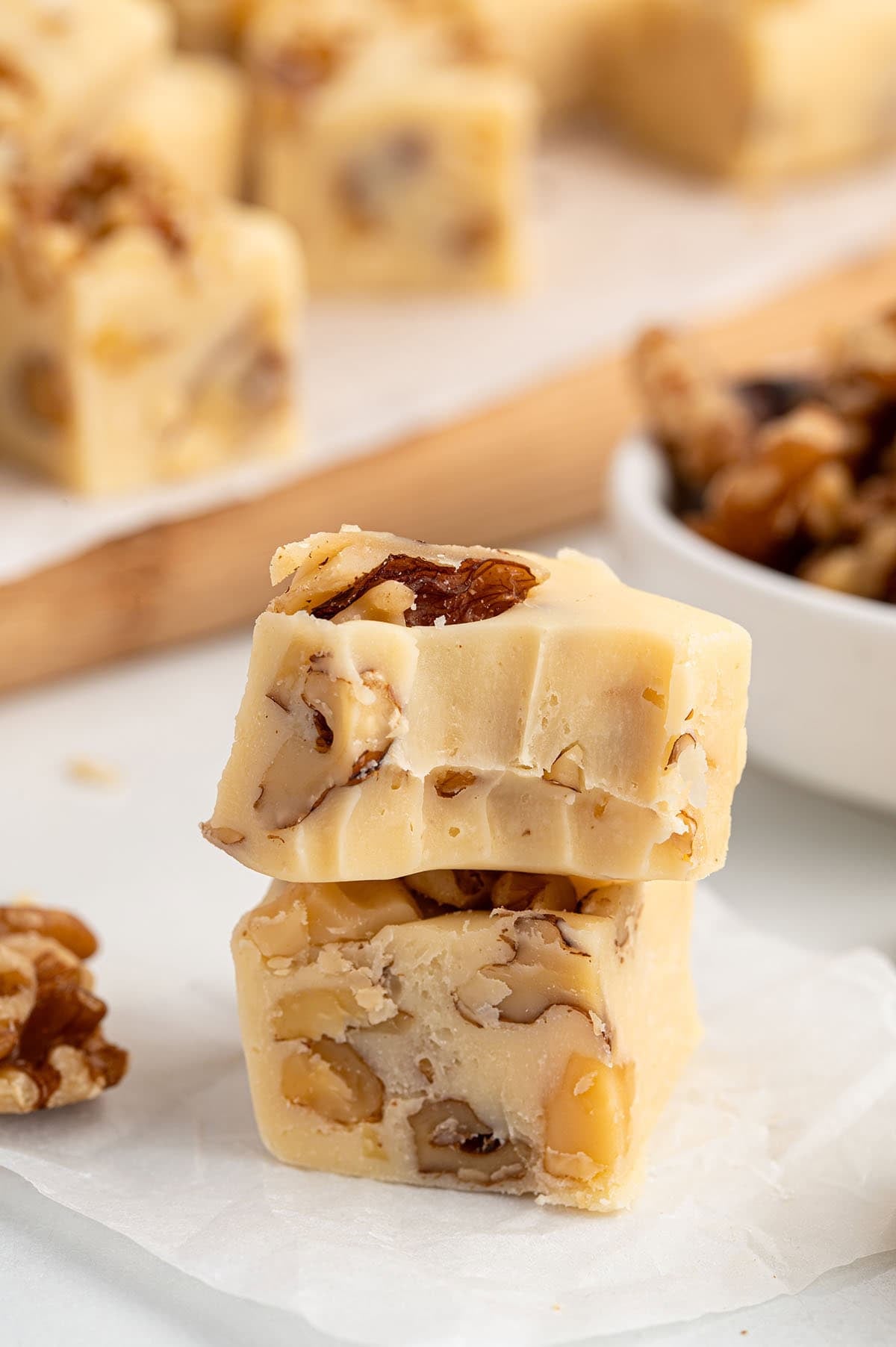 Two stacked maple walnut fudge squares with walnuts.