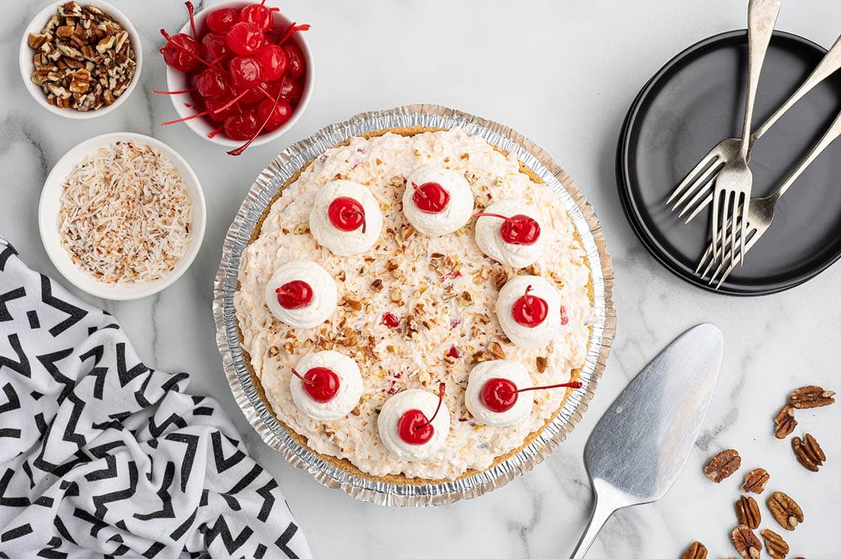 Millionaire pie topped with whipped cream, cherries, coconut, and pecans.