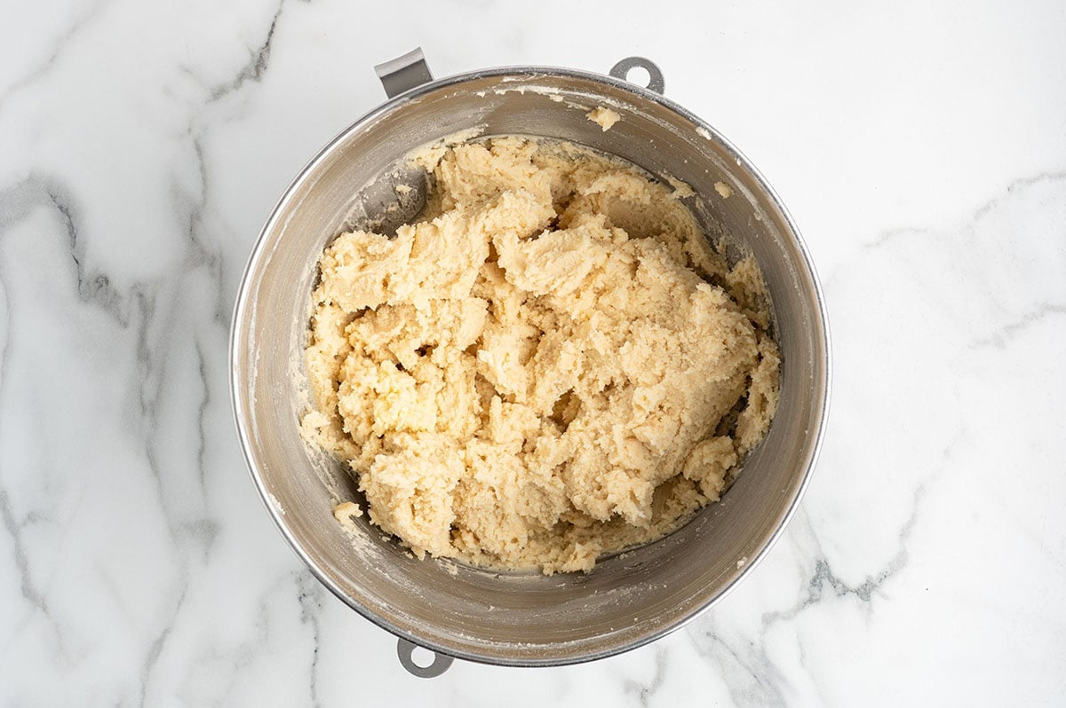 Spritz cookie dough in a stainless steel mixing bowl.